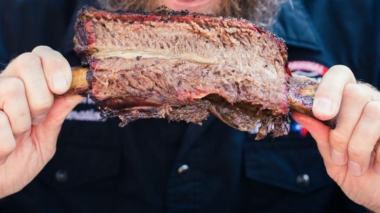 A man holding beef rib from Black's Barbecue.