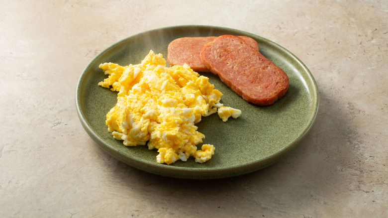 sliced Spam and scrambled eggs on a green plate