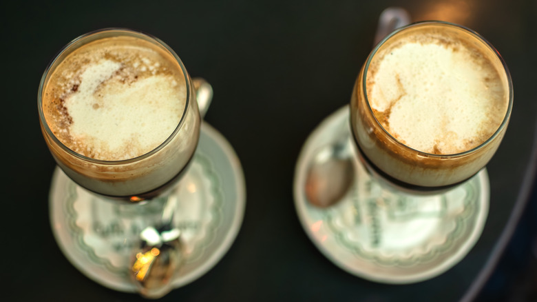 A top view of two mugs of bicerin on green and white saucers with spoons