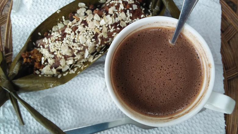 A mug of tsokolate on a napkin alongside a rice cake