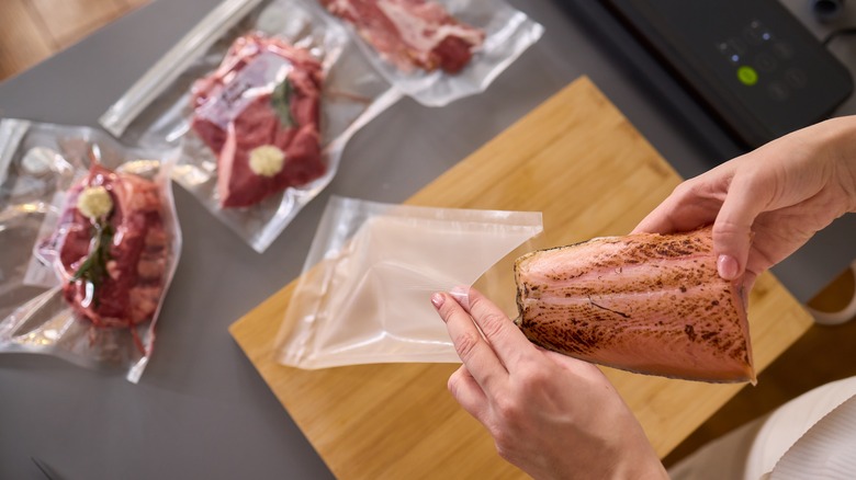 A salmon fillet being inserted into a sealable bag