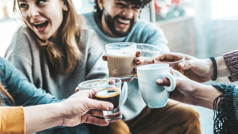 People laughing and holding various coffee drinks