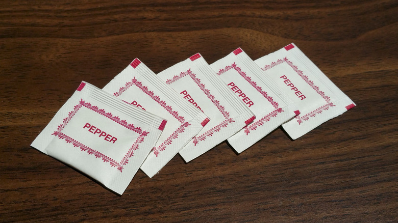 Packets of red pepper on a wooden table top