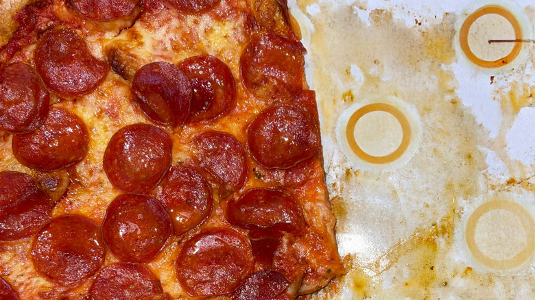 A half eaten pepperoni pizza in a greasy box