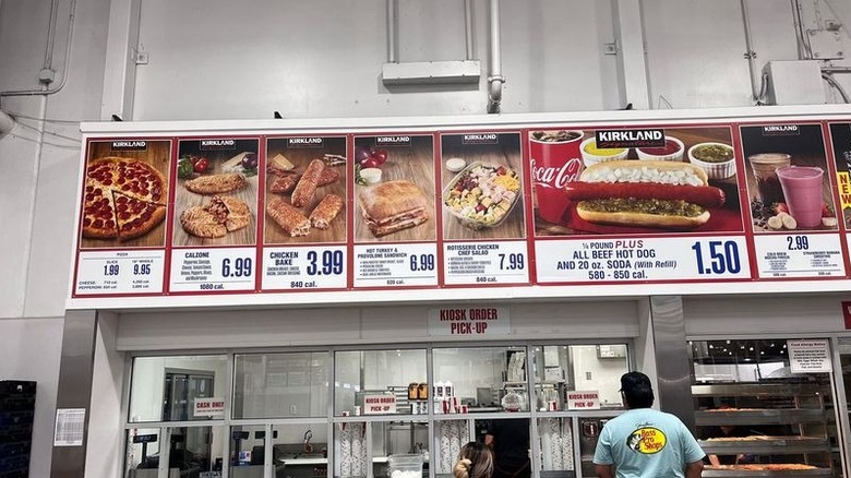 Person standing at window under Costco food court sign