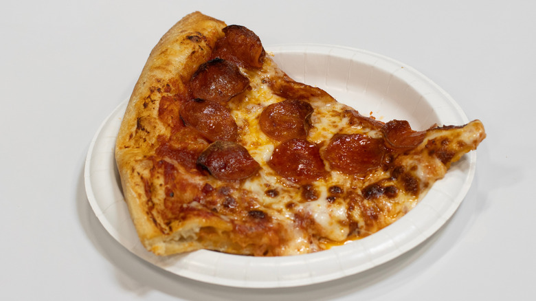 A paper plate with a large slice of pepperoni pizza from Costco