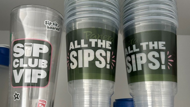 three stacks of clear, empty Panera drink cups labeled "Sip Club VIP" and "All the sips"