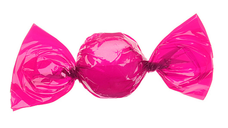 A bright pink candy wrapper covering a circular candy with the wrapper twisted at either end
