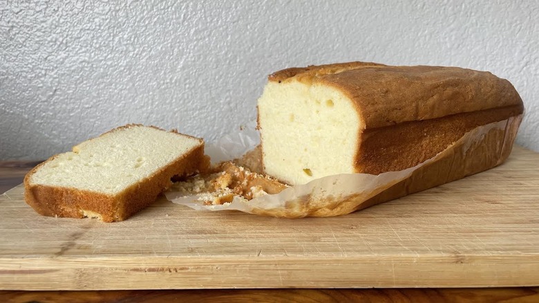A loaf and slice of Kirkland Signature All Butter Pound Cake on a wooden cutting board