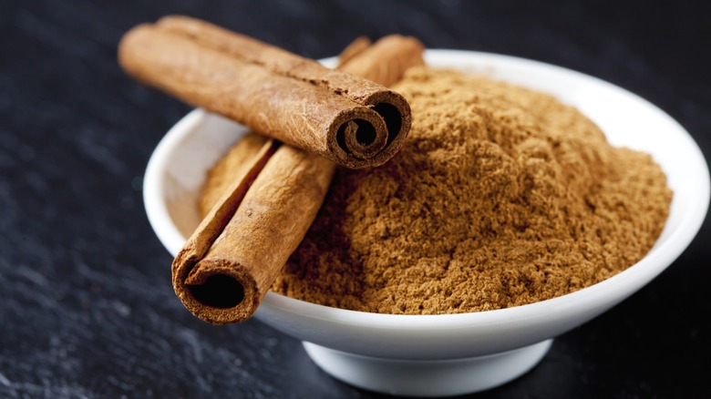 cinnamon sticks and powder in a white bowl