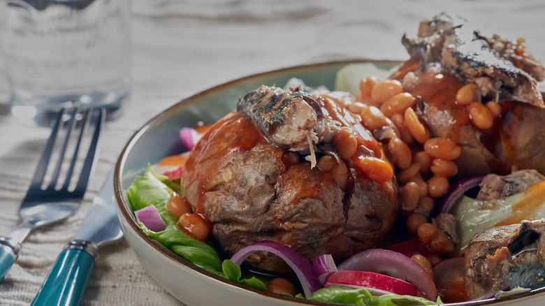 A baked potato with beans and sardines