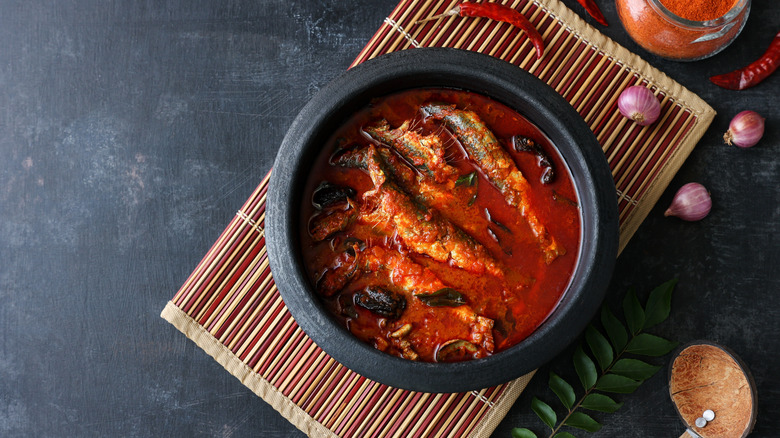 Sardine curry with shallots and spices on a dark background