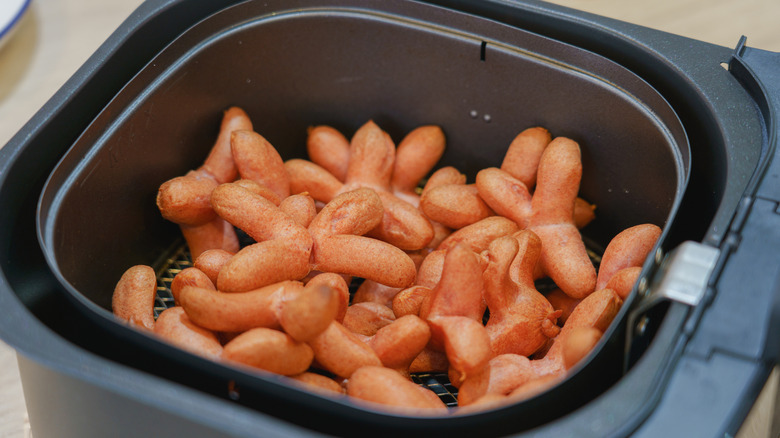 Mini hot dogs cook in an air fryer.
