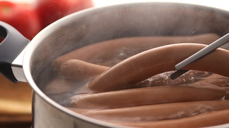 Hot dogs cook in a pot of boiling water.