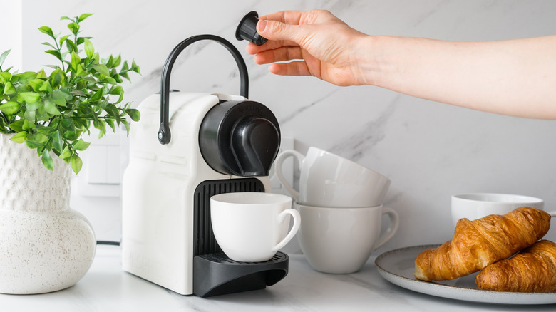 A person brewing pod coffee.