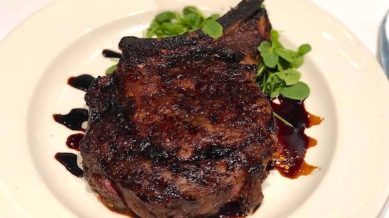 A close-up of Capital Grille's Porcini-Rubbed Bone-In Ribeye drizzled with its 15-Year Aged Balsamic vinaigrette