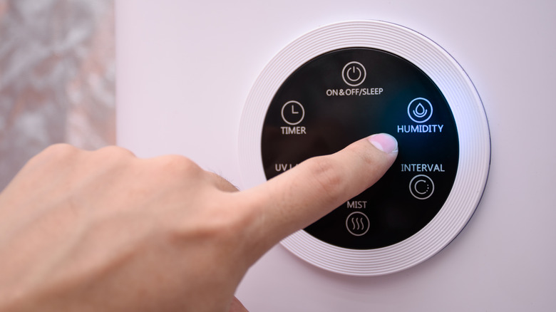 Hand adjusting the humidity settings on a wall humidifier