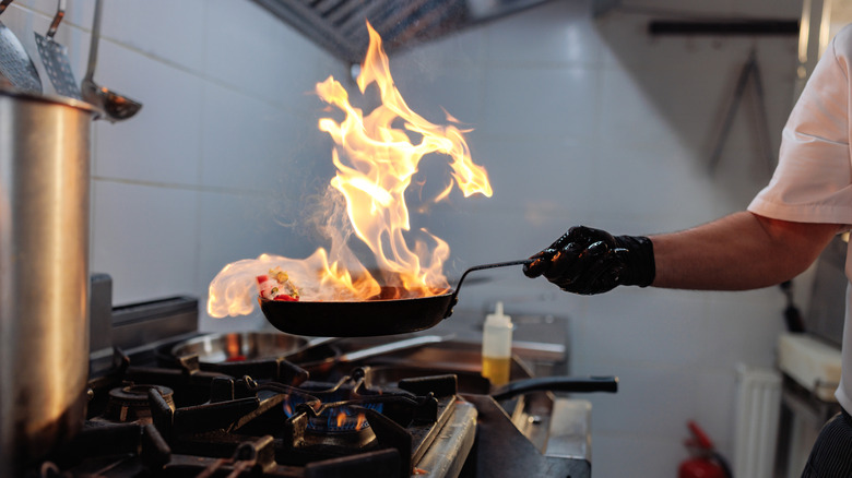 Chef with saucepan bursting in flames