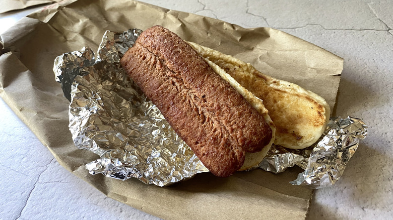 A Five Guys hot dog on top of aluminum foil and a paper bag