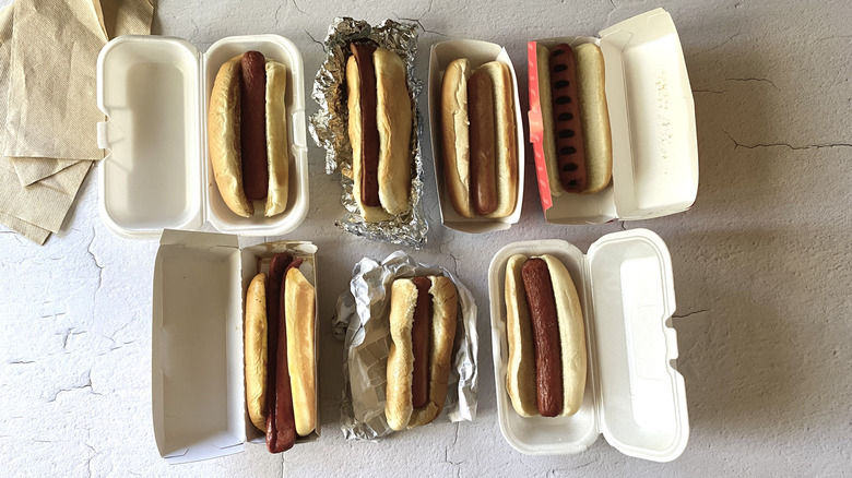 Two rows of hot dogs in their takeout containers and packagings