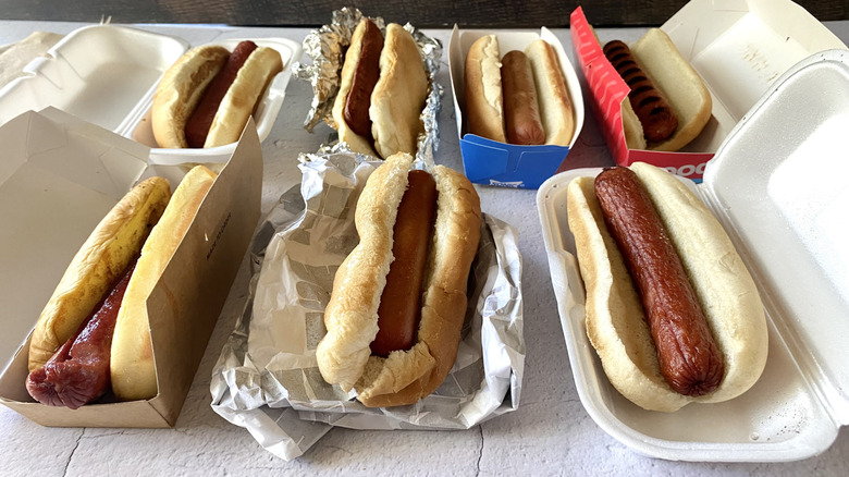 Two rows of hot dogs in their assorted takeout packagings