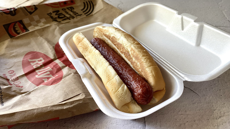 A Rally's hot dog in a styrofoam container on top of a paper bag
