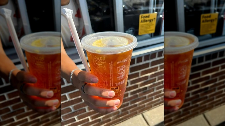 McDonald's worker handing sweet tea to guest in drive-thru