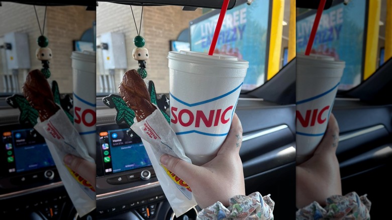 Hand holding Sonic cup of sweet tea and a pretzel in a car