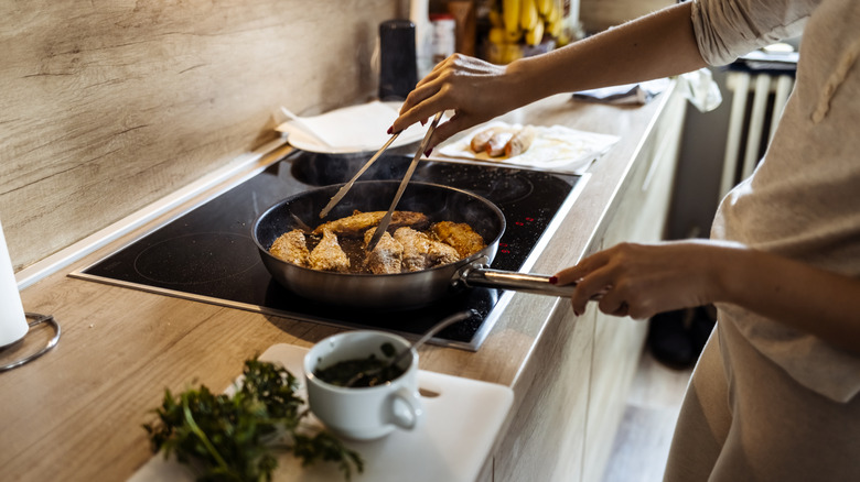 Woman cooking fish in kitchen