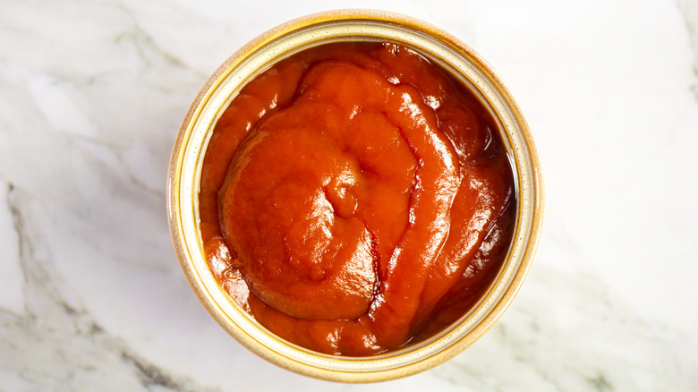 Close-up of open can of red tomato sauce from above