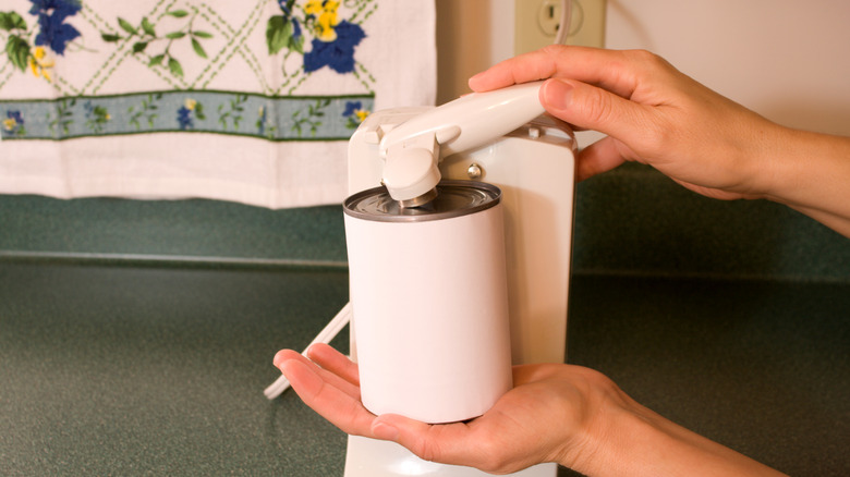 Person using electric can opener.
