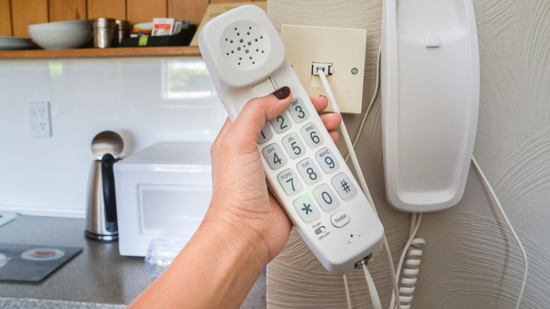 Person holding corded phone.