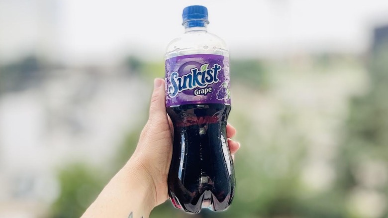 Hand holding bottle of Sunkist Grape Soda