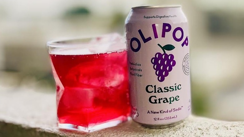 Glass and can of Olipop Grape Soda sitting on a ledge