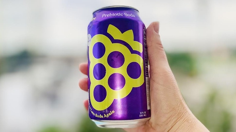 Hand holding can of Poppi Grape Soda