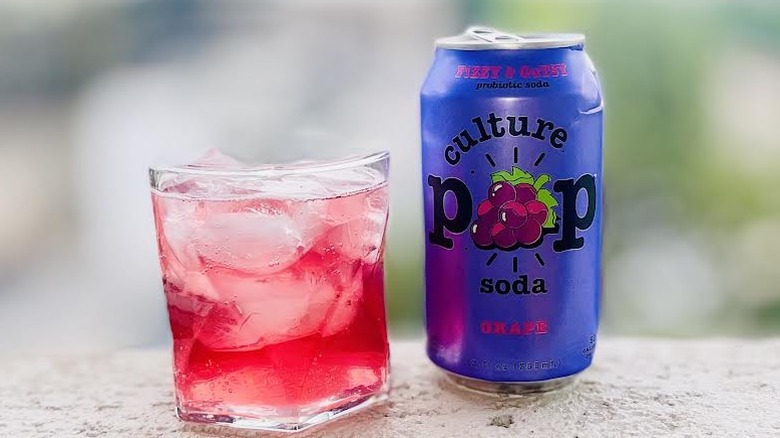 Can and glass of Culture Pop Soda Grape Soda sitting on a ledge