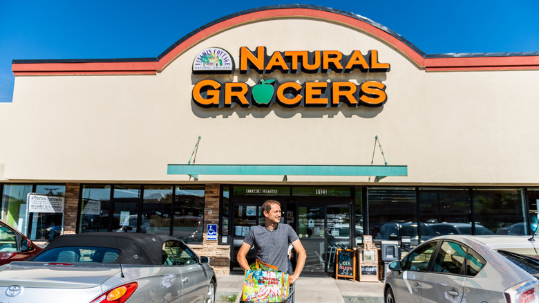 Smiling man leaving Natural Grocers with a full shopping cart