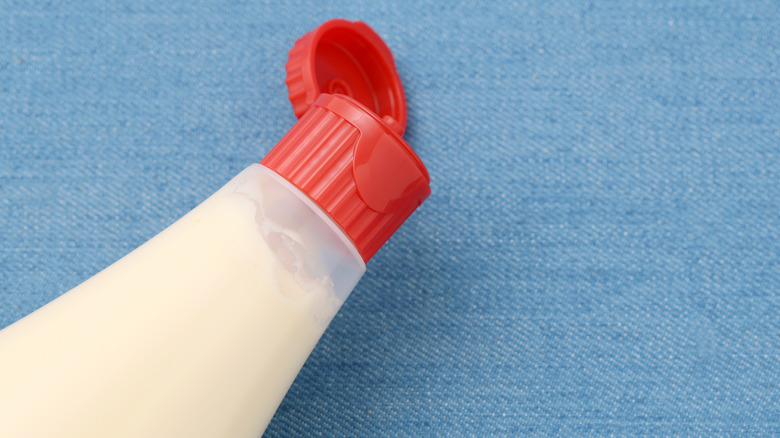 An open bottle of mayonnaise against a blue background