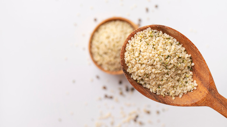 Close up of hemp seeds on a wooden spoon, with wooden bowl of hemp seeds in background