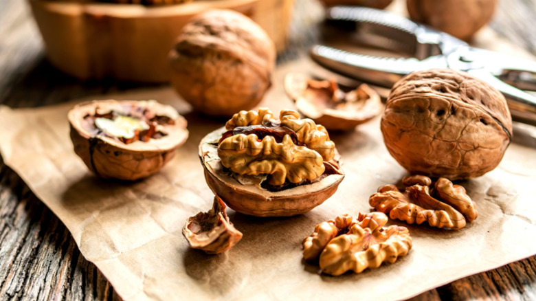 Whole and shelled walnuts on a wooden board