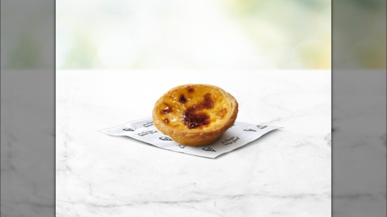 Two Portuguese egg tarts against a green background