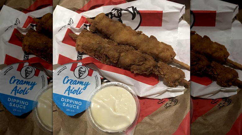 Two KFC Hot Rods with aioli dipping sauce on top of flattened KFC packaging