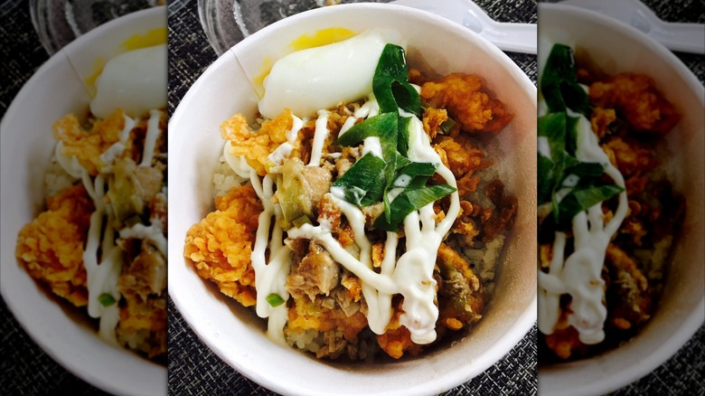 Bowl of KFC sisig with egg and scallions on woven gray surface