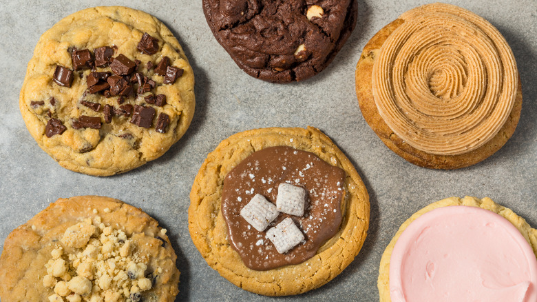 an array of Crumbl Cookies on a grey background