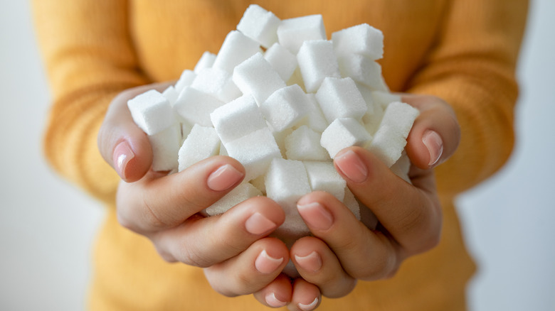 woman holding a pile of white sugar cubes