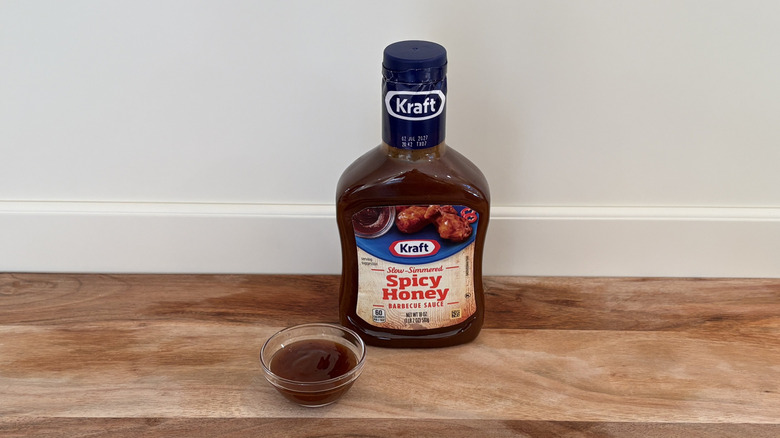 Kraft Spicy Honey BBQ sauce bottle next to dish of sauce on cutting board