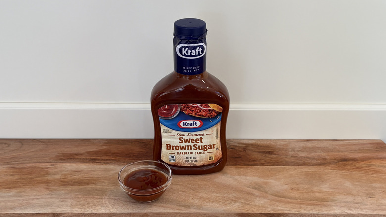 Kraft Sweet Brown Sugar BBQ sauce bottle on wooden cutting board with dish of sauce
