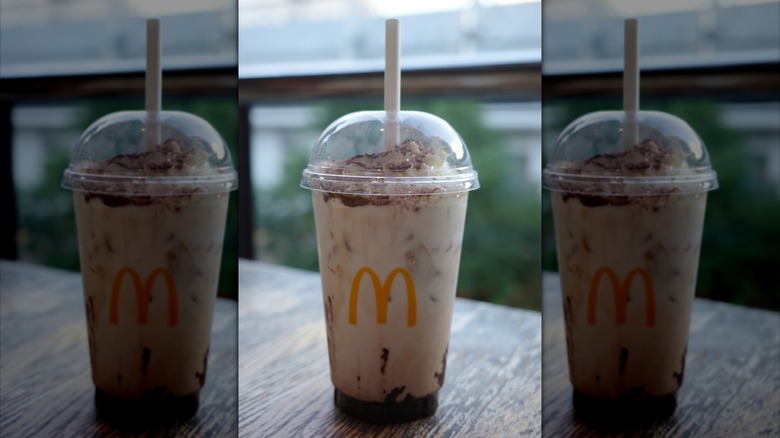 A chocolate McDonald's frappé sitting on a wooden table.
