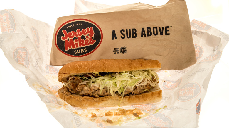 A Jersey Mike's cheesesteak sub with a wrapper on a white background