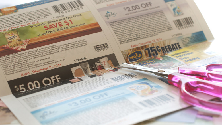Pair of pink scissors resting on sheet of coupons